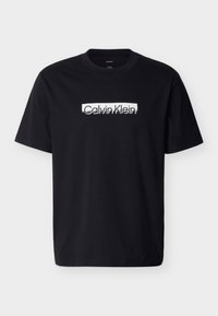 Μαύρο βαμβακερό t-shirt με λευκό λογότυπο Calvin Klein τυπωμένο στο στήθος. Κλασικός στρογγυλός γιακάς και κοντά μανίκια. Ομαλή υφή.