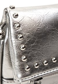 Borsa a tracolla argentata con finitura testurizzata. Presenta borchie metalliche arrotondate lungo il bordo e un compartimento con zip.