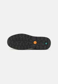 Suela de zapato de goma negra con un patrón de banda de rodadura profunda; presenta acentos en naranja y azul verde; superficie sólida y texturizada para agarre y durabilidad.