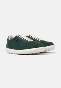 Green sneakers with suede and fabric upper, white rubber sole, blue accent on heel, and contrasting white laces.
