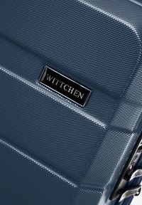 Modrá tvrzená kufr s texturovaným povrchem a diagonálními drážkami. Černé kovové logo "WITTCHEN" a robustní zipové detaily.