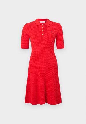 Vestido tipo polo rojo con un patrón de punto texturizado, mangas cortas, cuello plano y tres botones dorados en el escote.