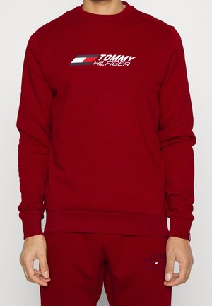 Rotes Sweatshirt mit Rundhalsausschnitt, gerippten Bündchen und Saum. Mit "TOMMY HILFIGER" Logo und Flaggen-Design auf der Vorderseite. Weicher Stoff.
