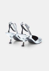 Hopeiset metalliset slingback-kengät, joissa on pyöreä kärki ja kolmiomainen korko. Sileä pinta ja säädettävä hihnaviimeistely parantavat istuvuutta.