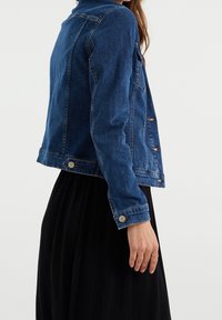 Jeansjacka i mörkblått med slim fit, knäppning med knappar och klassisk krage. Innehåller sidofickor och silverfärgad hårdvara.