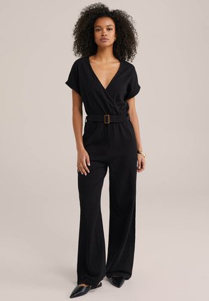Zwarte wijde jumpsuit met korte mouwen, diepe V-hals, gestructureerde stof, ceintuurlijn en een subtiel verticaal patroon.