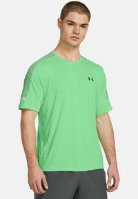 Zelené športové tričko s krátkymi rukávmi, okrúhlym výstrihom a textúrovanými sivými akcentmi na pleciach. Na hrudi sa nachádza logo Under Armour.