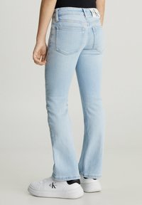 Jeans flare in denim azzurro chiaro con vita a media altezza e texture minimamente logorata. Presentano tasche posteriori a toppa e una vita con marchio.