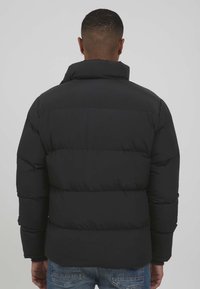 Black puffer jacket with a high collar, featuring quilted sections and a smooth texture. Simple design, suitable for warmth and layering.