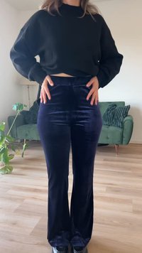 Svart kortermet genser og marineblå fløyelsbukser med vide ben, glatt tekstur, tilpasset midje, bred benåpning, brukt med svarte sko, innendørs. 