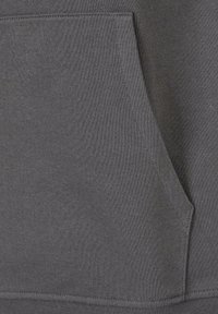 Nahaufnahme einer grauen Kängurutasche aus Stoff mit sichtbaren Nähten an einem Kleidungsstück.