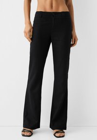 Black wide-leg pants made of lightweight fabric, featuring a front button closure, belt loops, and a smooth texture.