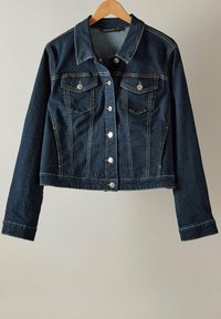 Tummansininen farkkutakki, jossa on istuva malli, kaksi rintataskua, metalliset napituskiinnitykset ja kontrastiväriset keltasiimat. Pitkät hihat, joissa on nappikiinnitys.