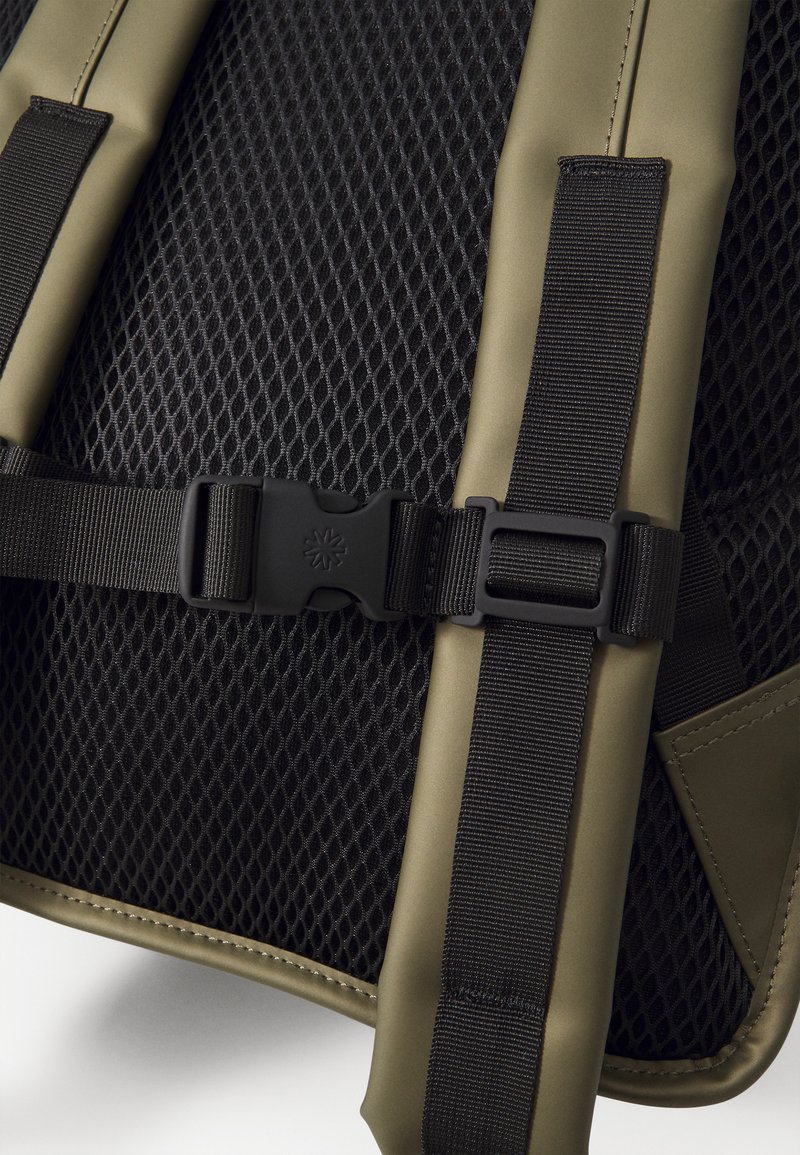 Matériau en maille noire avec des accents vert olive, présentant des bretelles ajustables et une boucle en plastique noir, couture détaillée autour des bords.