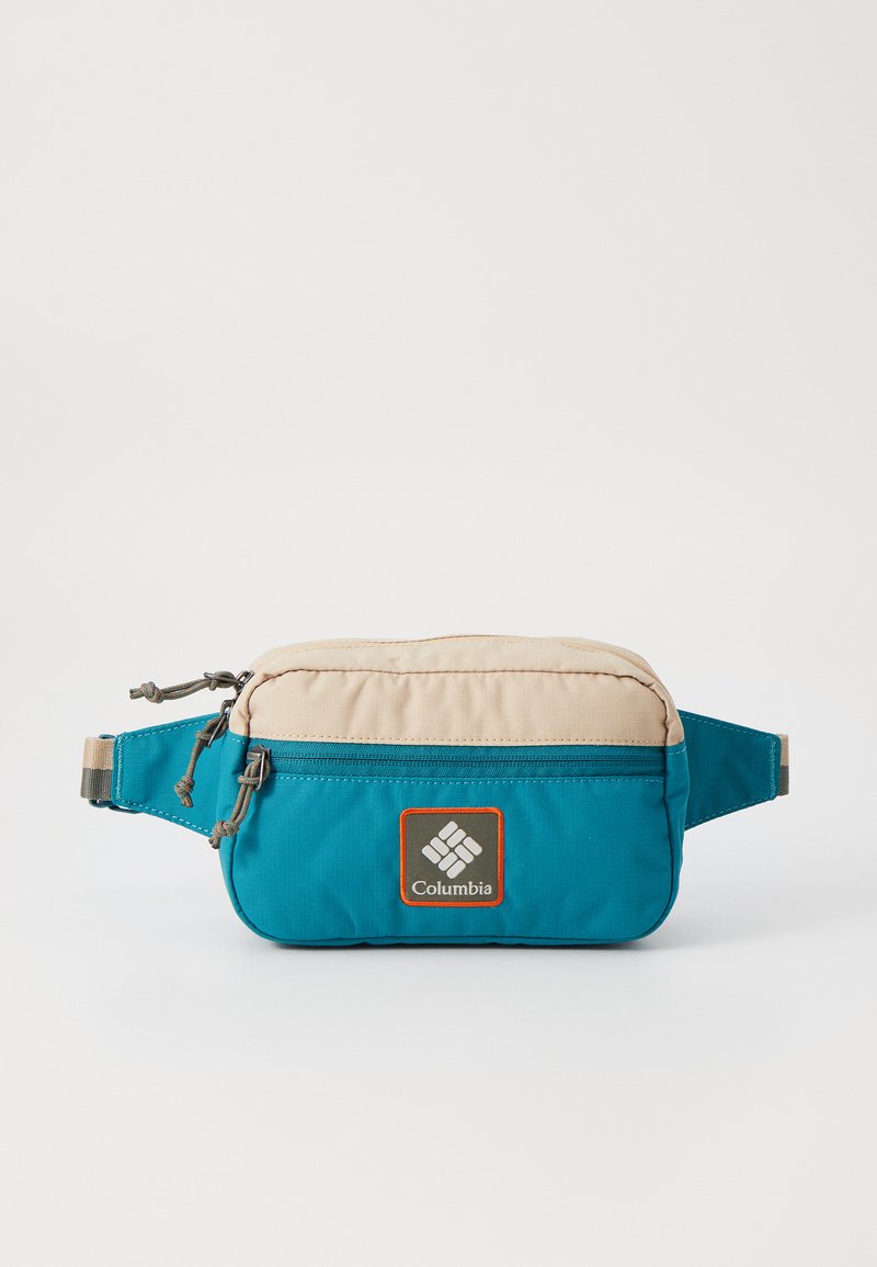 Teal and beige fanny pack featuring a textured exterior, front zipper pocket, and Columbia logo patch with orange border. Adjustable strap included.