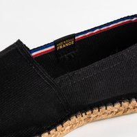Espadrille en toile noire avec une semelle en jute, dotée d'une doublure intérieure aux rayures colorées et d'une étiquette indiquant "FABRIQUÉ EN SOLE, FRANCE."