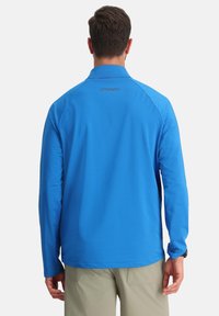Camicia blu a maniche lunghe realizzata in tessuto leggero con finitura testurizzata, dotata di colletto e logo "SPYDER" sul retro.
