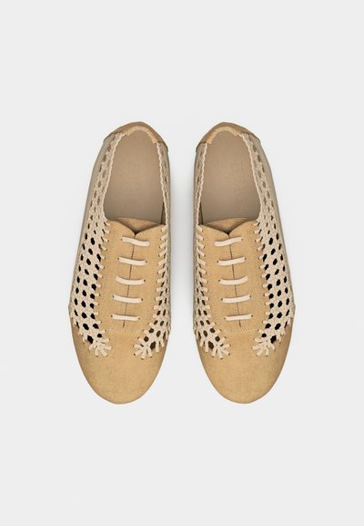 Paire de chaussures beige en cuir tissé, à enfiler, avec bouts fermés et lacets décoratifs sur fond blanc.