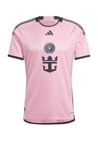Maillot de football rose à manches courtes avec des accents noirs, présentant un logo circulaire du club et un emblème foncé à l'avant, fabriqué en matériau respirant.