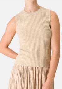Beige bezramenný top s ribovanou texturou a malými texturovanými tečkami, který má kulatý výstřih a přiléhavý siluetu.