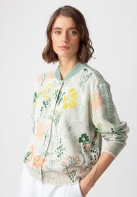 Lätt texturerad cardigan i pastellgrön, med blommönster i gult, rosa och grönt. Knäppning framtill och ribbade muddar.