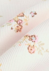 Rippstoff in sanftem Pink mit floralen Mustern in Pastellfarben, ausgestattet mit feinen Details in braunen, rosa und blauen Farbtönen. Texturierte Oberfläche.