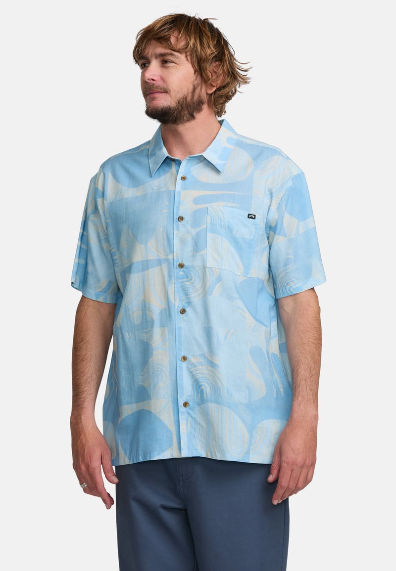 Košela na button-up s krátkymi rukávmi z bledomodrej látky, ktorá má abstraktné krémové vzory, predné vrecko a hnedé gombíky. Hladká textúra.