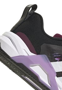 Crni tekstilni gornji deo sa ljubičastim i belim akcentima, debeli beli potplat, i teksturirana crna gumena outsole sa uzorkom gaznoga sloja.