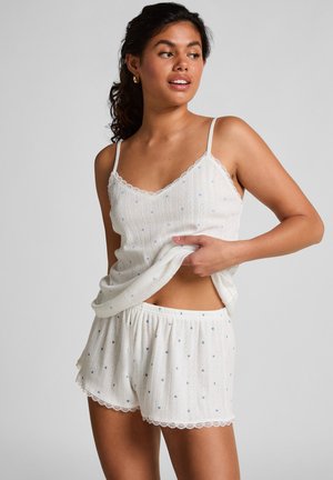 White two-piece pajamas featuring a lace-trimmed tank top and shorts with blue geometric patterns. Soft, lightweight fabric.