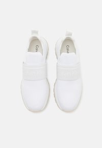Chaussures de sport blanches avec une tige en mesh, une sangle élastique portant la mention "Calvin Klein" et une semelle légère. Design minimaliste avec une texture lisse.