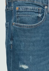 Lichtblauwe denim spijkerbroek met een verouderd ontwerp, gescheurde patches, vijf zakken stijl en contrasterende stikseldetails.