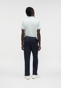 Πόλο μπλούζα σε ανοιχτό μπλε, συνδυασμένη με σκούρο μπλε σκούρο παντελόνι φόρμας. Απλός σχεδιασμός, κοντά μανίκια, ελαστική μέση και λευκά αθλητικά παπούτσια.