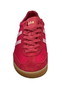 Red sneaker featuring a fabric upper with suede accents, two white stripes, round laces, and a gum rubber sole. Gold logo on the tongue.