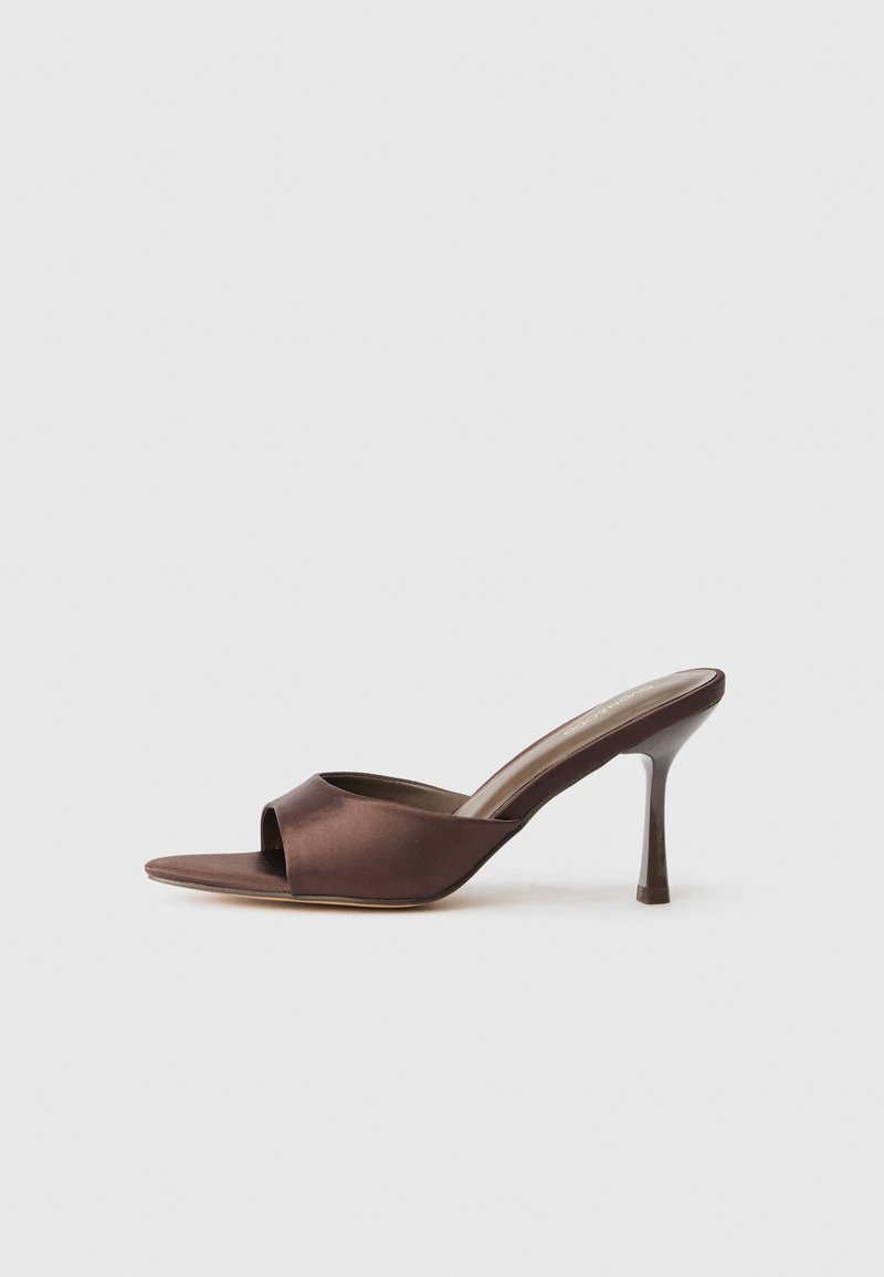 Mule en satin marron à bout ouvert avec un talon fin de hauteur moyenne et une conception à enfiler sur fond blanc uni.