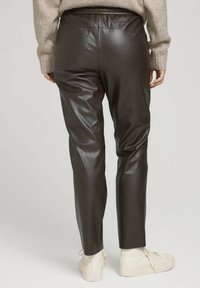 Bruna faux läderbyxor med slim fit, som har en elastisk midja, slät textur och avsmalnande ben, kombinerat med vita hög-top sneakers.