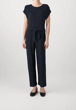 Marineblauw geribbelde jumpsuit met korte mouwen, ceintuurdetail in de taille en recht gesneden broekspijpen. Zachte textuur en minimalistisch ontwerp.