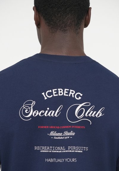 T-shirt en coton bleu marine avec texte imprimé en blanc et rouge au dos, incluant « ICEBERG Social Club » et « Milano Italia Established 1974 ».