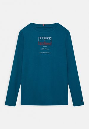 Langærmet teal skjorte med Tommy Hilfiger logo og teksten "New York Established MCMLXXXV" trykt på forsiden.