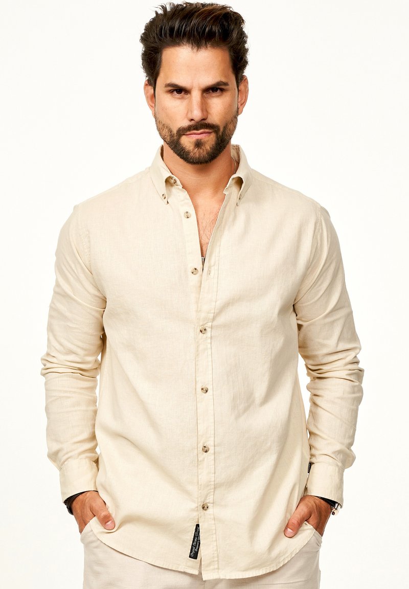Beige Leinen-Hemd mit langen Ärmeln, leichtem Textur und braunen Knöpfen. Verfügt über einen klassischen Kragen und ein dezentes Branding-Detail am Saum.