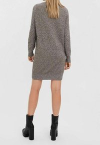 Robe en maille grise à manches longues, coupe droite et ourlet côtelé. Portée avec des bottines noires à talons épais pour le contraste.