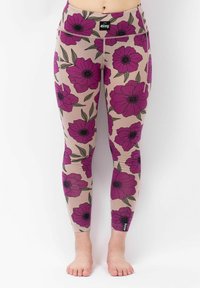 Blumige Leggings mit einem beigen Hintergrund, verziert mit kräftigen lila Blumen und grünen Blättern, aus dehnbarem Stoff und mit einem schwarzen Logo-Tag.