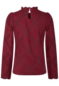 Burgundin pitkähihaisen paidan, jossa on teksturoitu pinta, joka esittelee geometrisiä muotoja, röyhelökaulus ja avainhole-tausta nappikiinnityksellä.