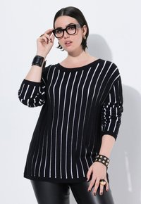Gestreifter Pullover in Schwarz-Weiß mit lockerer Passform, weitem Ausschnitt und hochgerollten Ärmeln. Besitzt eine glatte Textur und eine lange, gerade Silhouette.