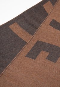 Sciarpa marrone e grigio scuro con trama liscia. Presenta forme geometriche e un dettaglio di bordo cucito. Il tessuto sembra morbido e leggero.