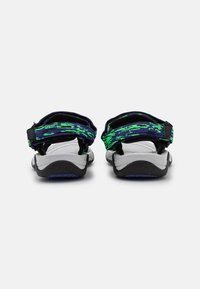 Sandalias de talón abierto con correas estampadas en verde y negro, plantilla blanca y suela negra. Cuentan con correas ajustables para mayor comodidad.