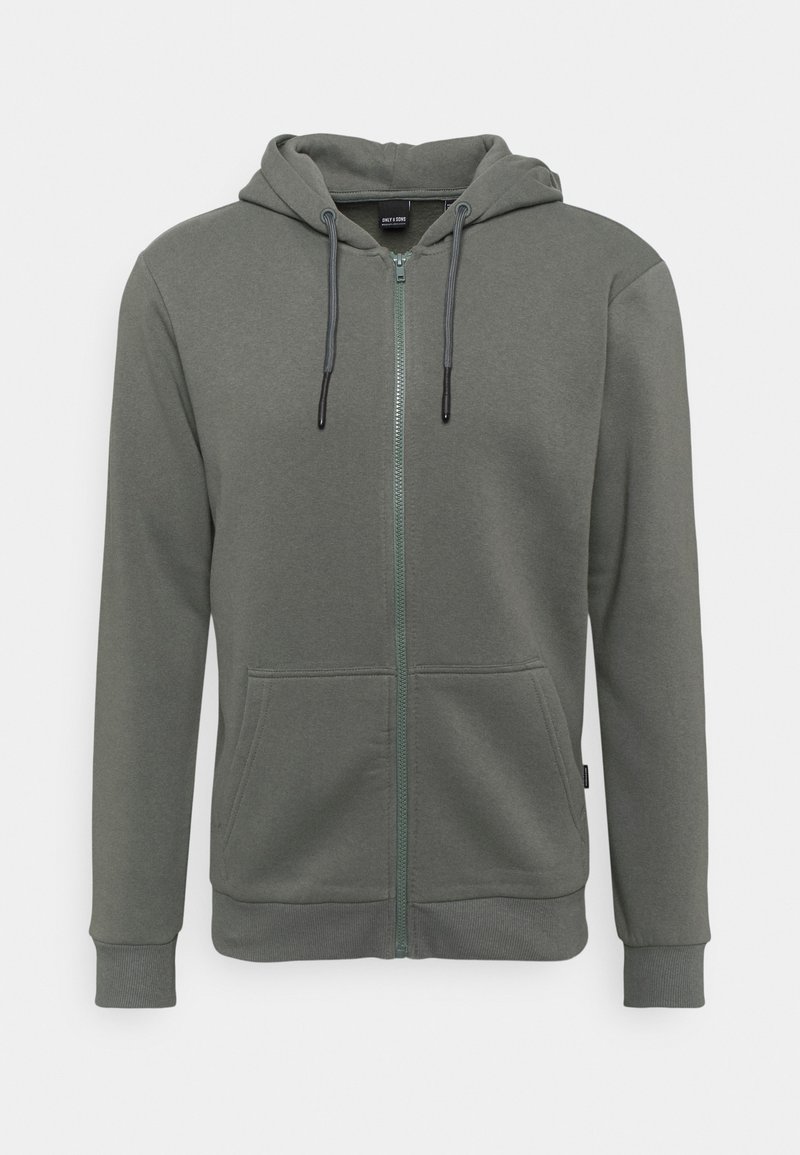Khaki zip-up kapuca s vrvico, z dvema sprednjima žepoma in rebrastimi manšetami; izdelan iz mehke, gladke tkanine z subtilno teksturo.