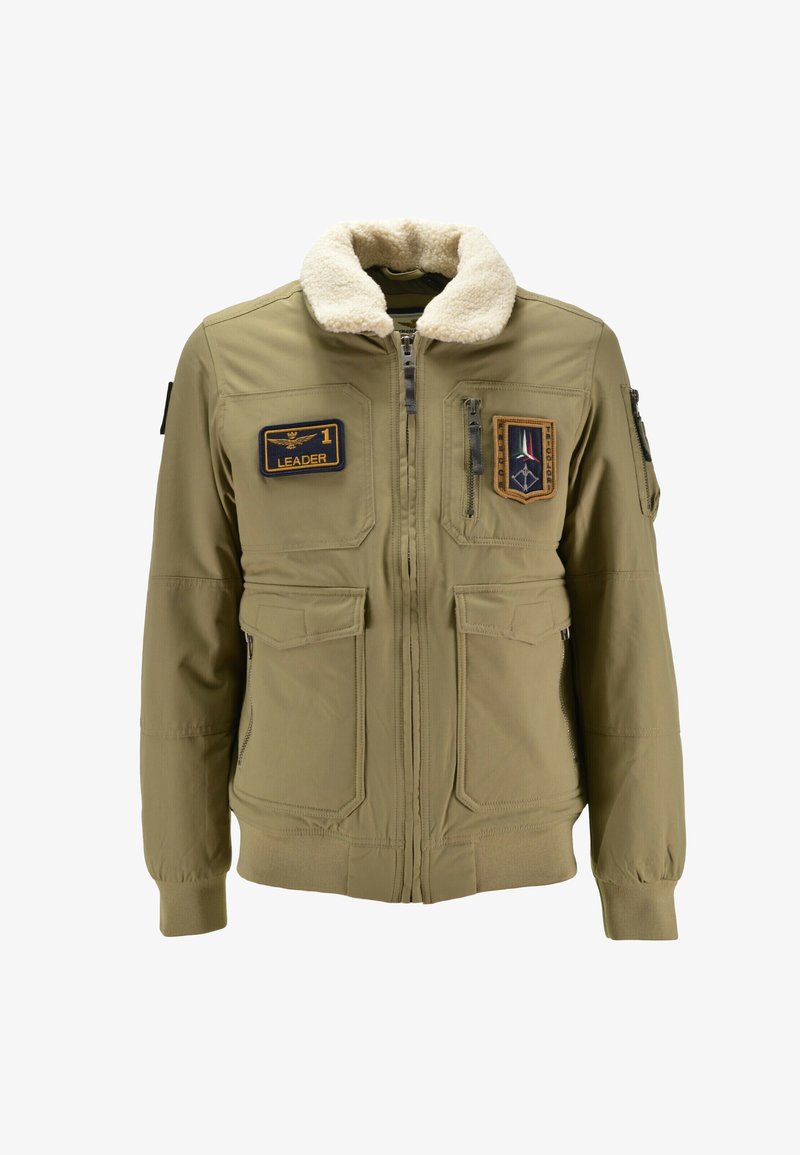 Giacca bomber khaki con colletto in finta shearling, multiple tasche e toppe con la scritta "LEADER" e altri distintivi.