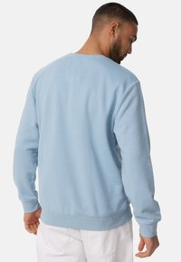 Sudadera azul clara de manga larga y cuello redondeado. Presenta puños y dobladillo de canalé, hecha de una suave tela texturizada.
