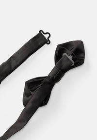 Μαύρη σατέν παπιγιόν με υφή, διαθέτει κομψό ρυθμιζόμενο λουρί και πλαστικά υλικά για ασφαλή κλείσιμο.