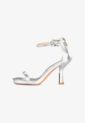 Silberne Sandale mit High Heels und Knöchellriegel, dekoriert mit klaren Edelsteinen und einem dünnen Riemen über den Zehen.